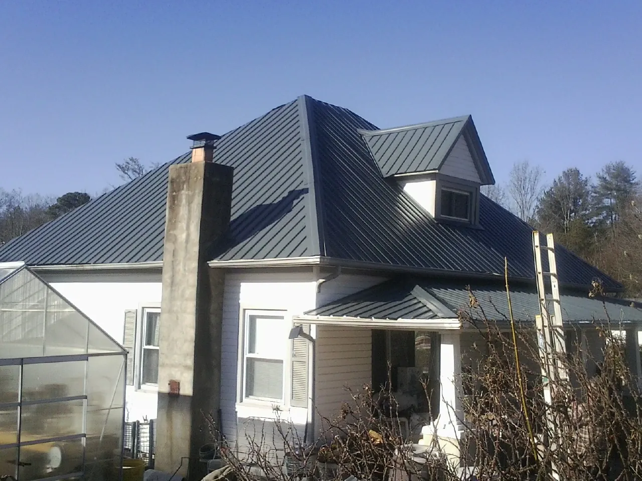Dark blue standing seam metal roof on a white farmhouse with dormer — Slate & Tile Roof Repair by Roofing Brothers in Pittsburgh