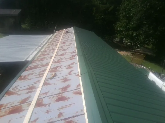Old rusted panels beside newly installed green metal roofing — Wind Damage Roof Repair by Roofing Brothers in Pittsburgh