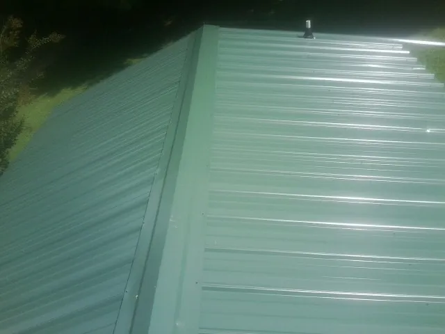 New green metal panels meeting at the ridge of a roof — Flat Roof Repair work by our crew in Pittsburgh
