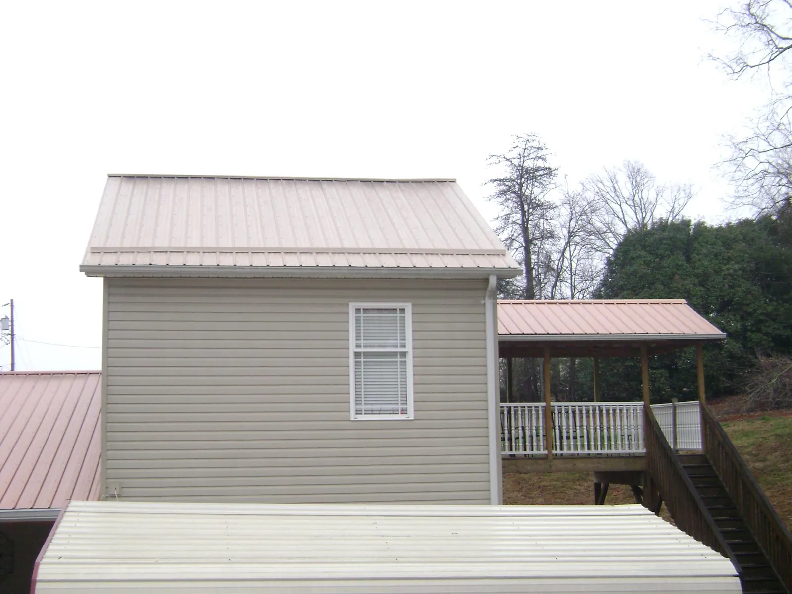 Tan metal roofs on a two story addition and attached porch, from a Roof Replacement job in Pittsburgh