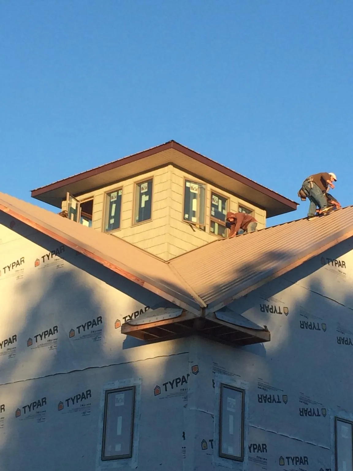 Roofers working around a rooftop cupola on a new metal roof at sunset — Roof Waterproofing in Pittsburgh by Roofing Brothers